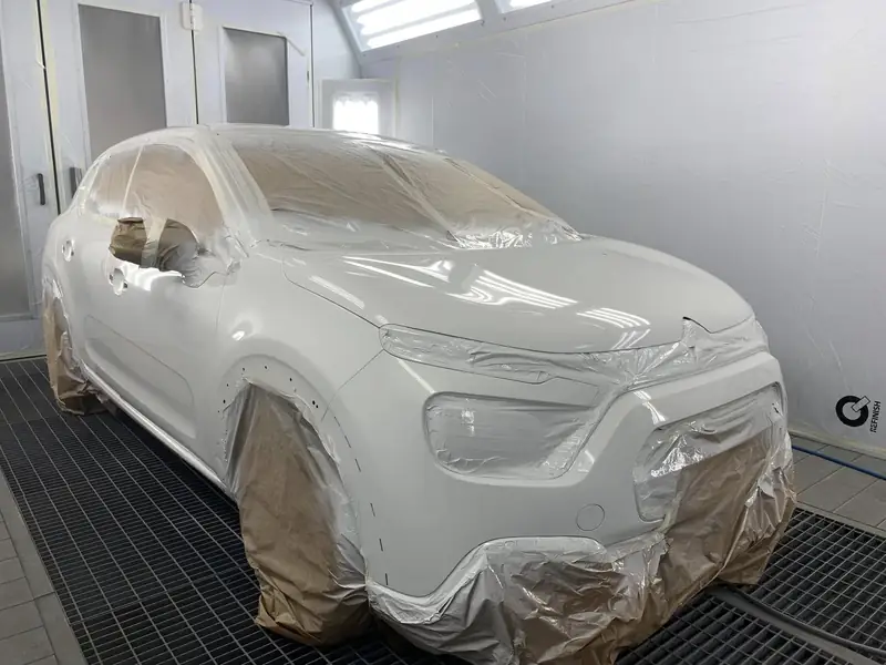Citadine blanche masquée et apprêtée en cabine de peinture, carrosserie AM Koncept à Persan