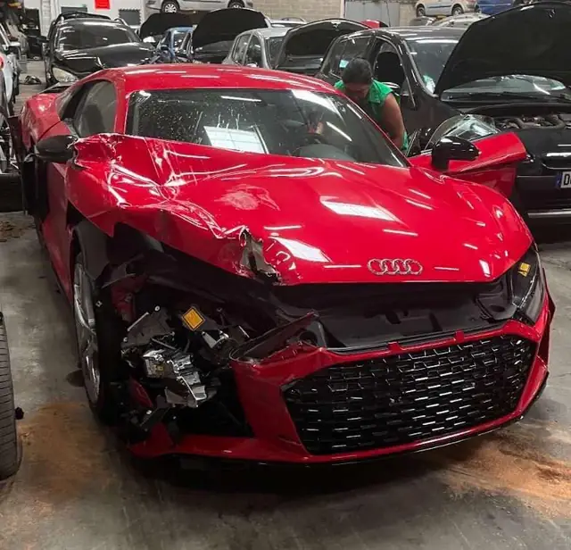 Audi rouge accidentée à l'avant, prise en charge à l'atelier